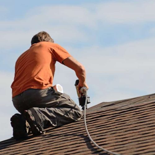 Building contractor putting the asphalt roofing on a large commercial apartment building development